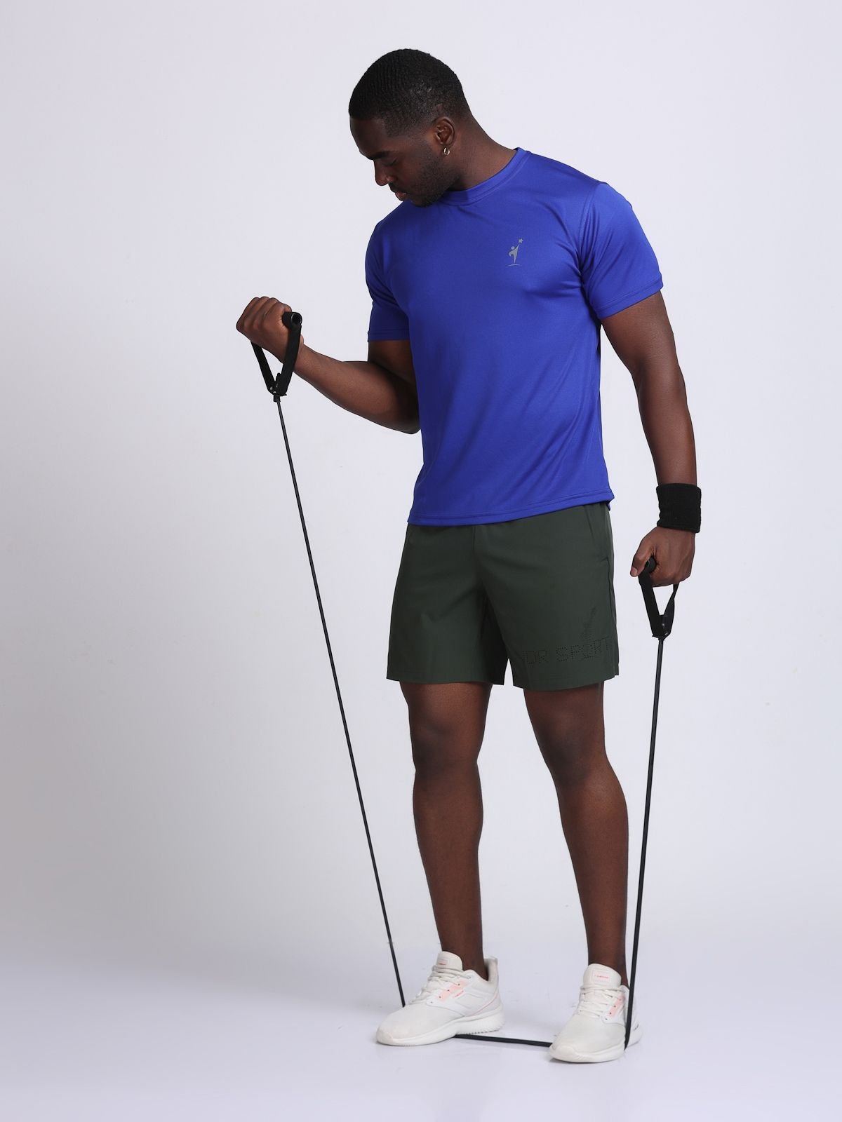 Full-body workout shot of a man wearing olive green athletic Feather LaserTech shorts with a blue tee and resistance band.