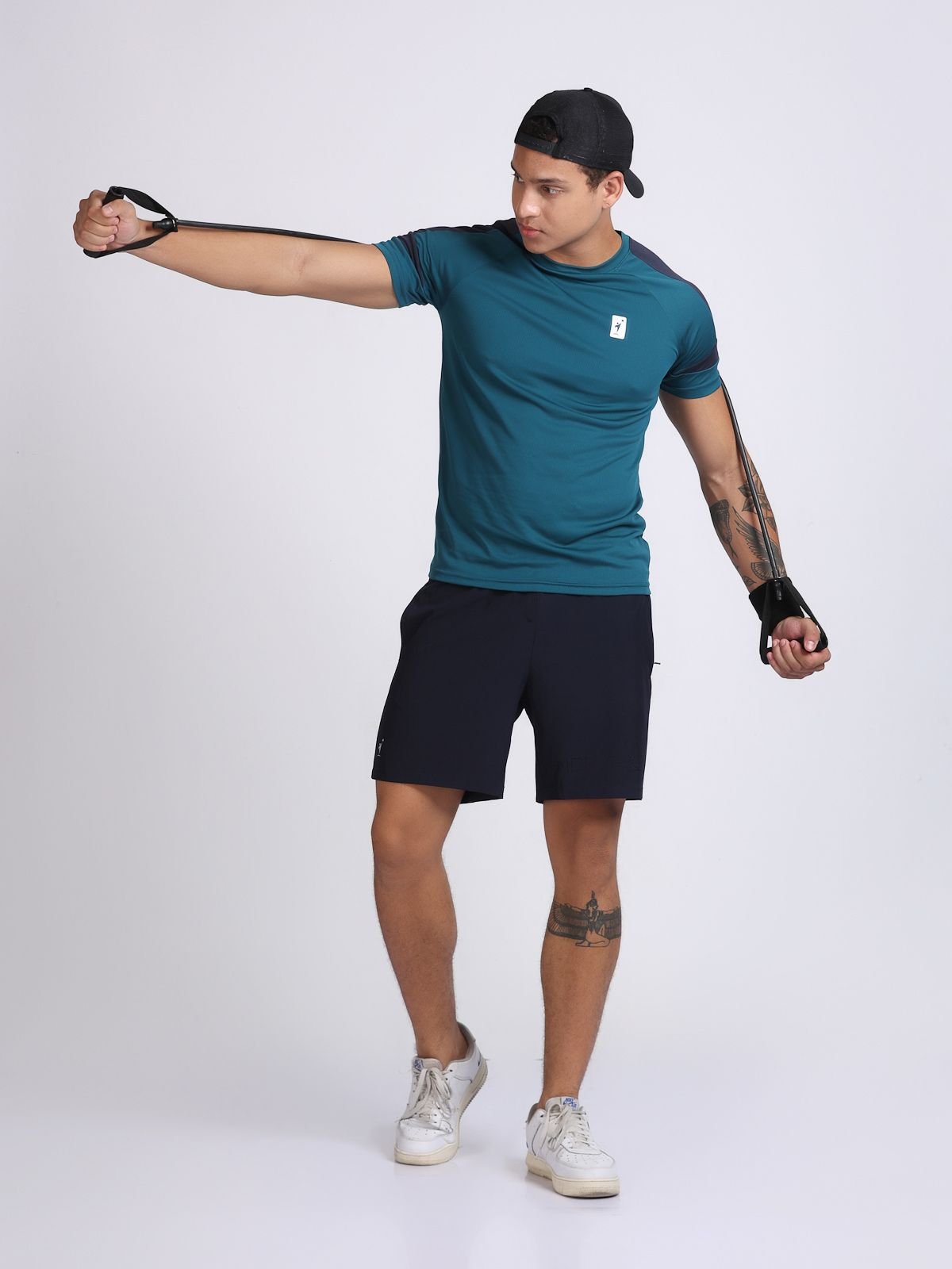 Full-body action shot of a man stretching a resistance band wearing a teal athletic t-shirt AirFeel and navy shorts.
