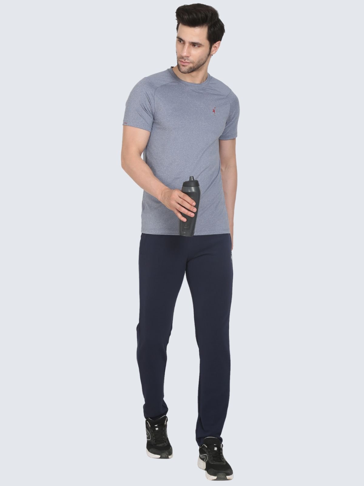 Full-body male model in grey cool n comfort tee wearing navy regular stretch pants, holding a black water bottle on a white background